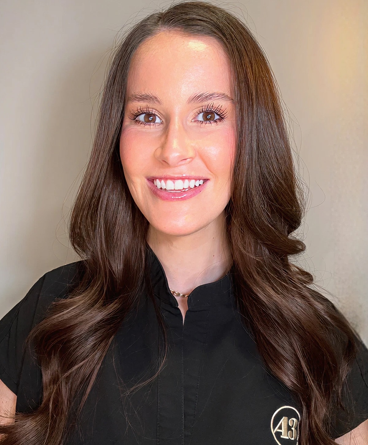 Smiling woman with long brown hair in black shirt.
