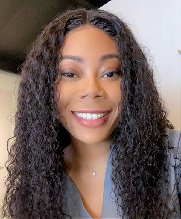 Smiling woman with curly hair, indoor setting.