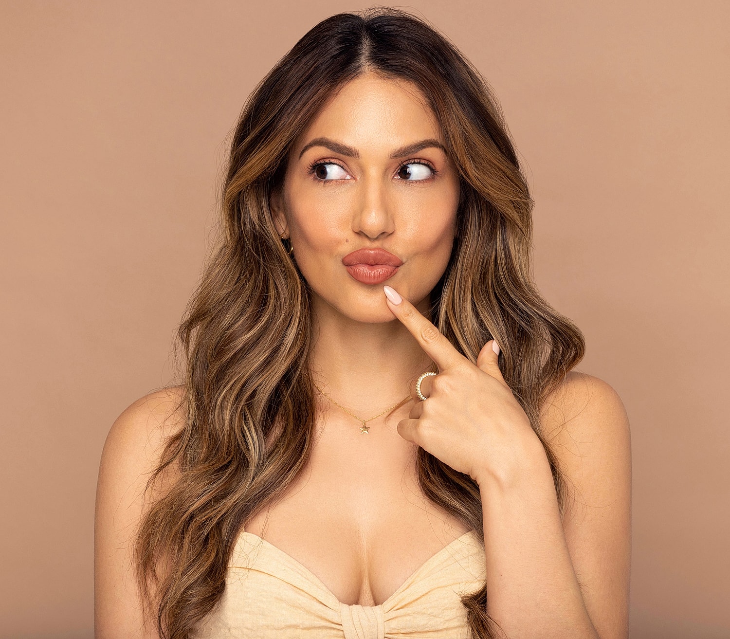 Woman playfully posing with finger on lips.