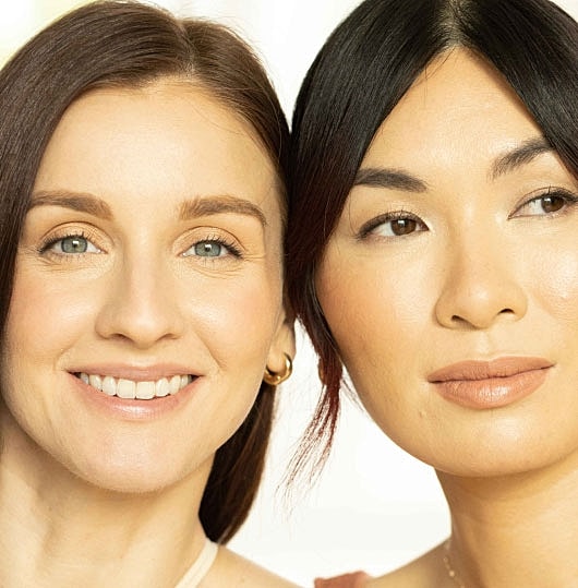 Two women smiling together, close-up portrait.